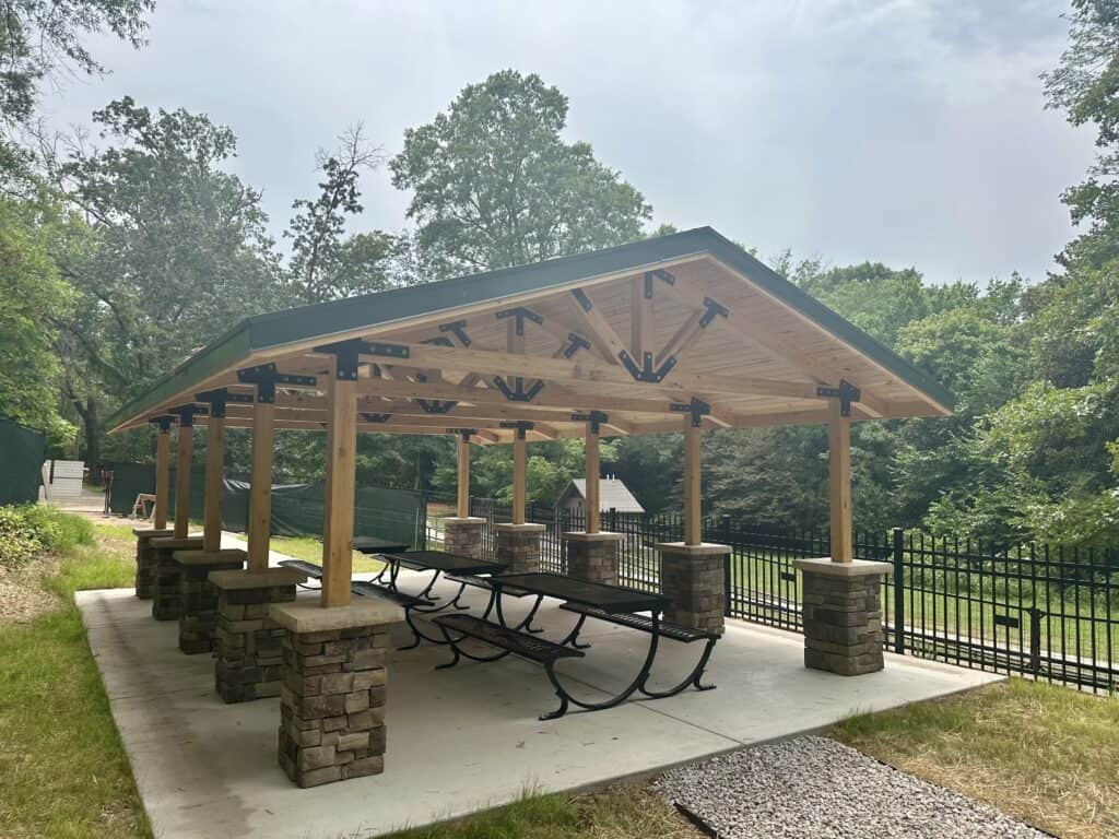 Park pavilion shelter with metal roof and concrete pad in public park setting