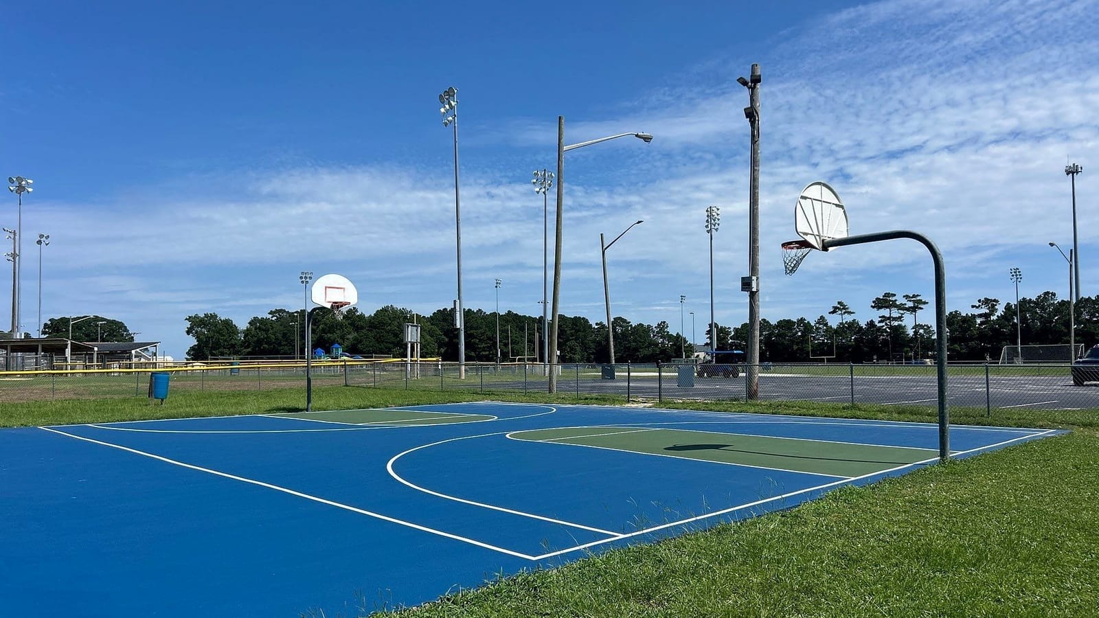 Finished blue and green public basketball courts under light poles with fresh white lines — Cedar Point, NC